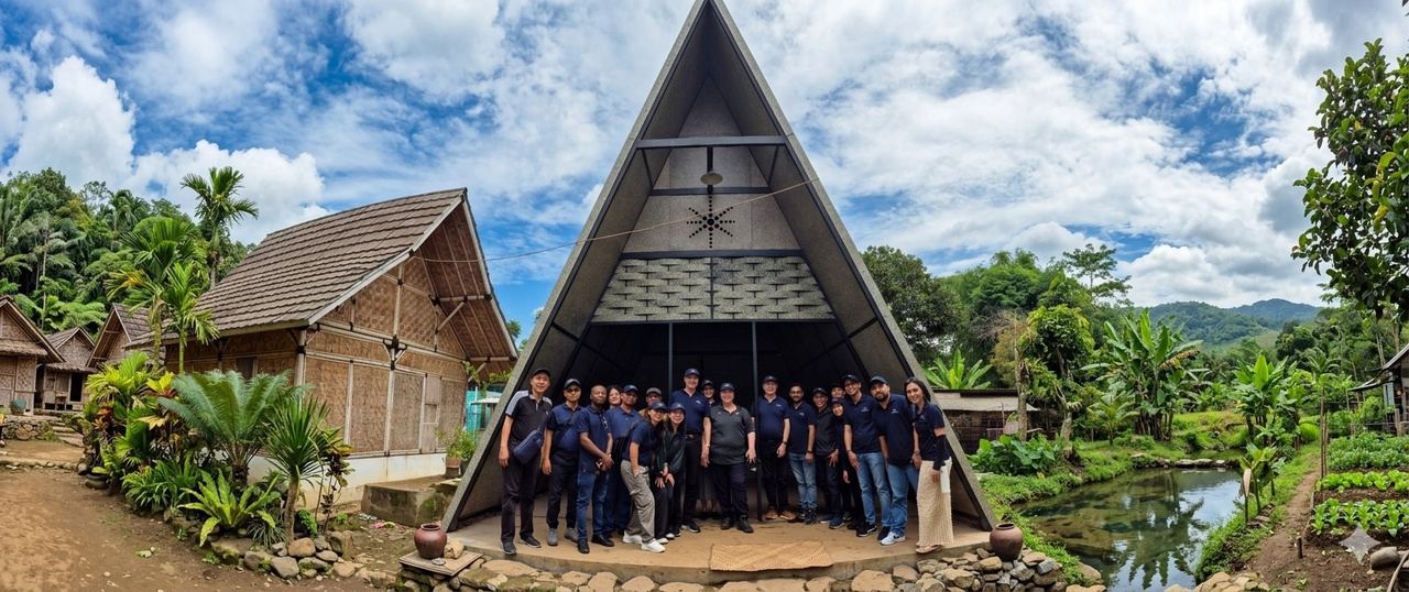 Team standing in front of an A-frame structure built from recycled boards